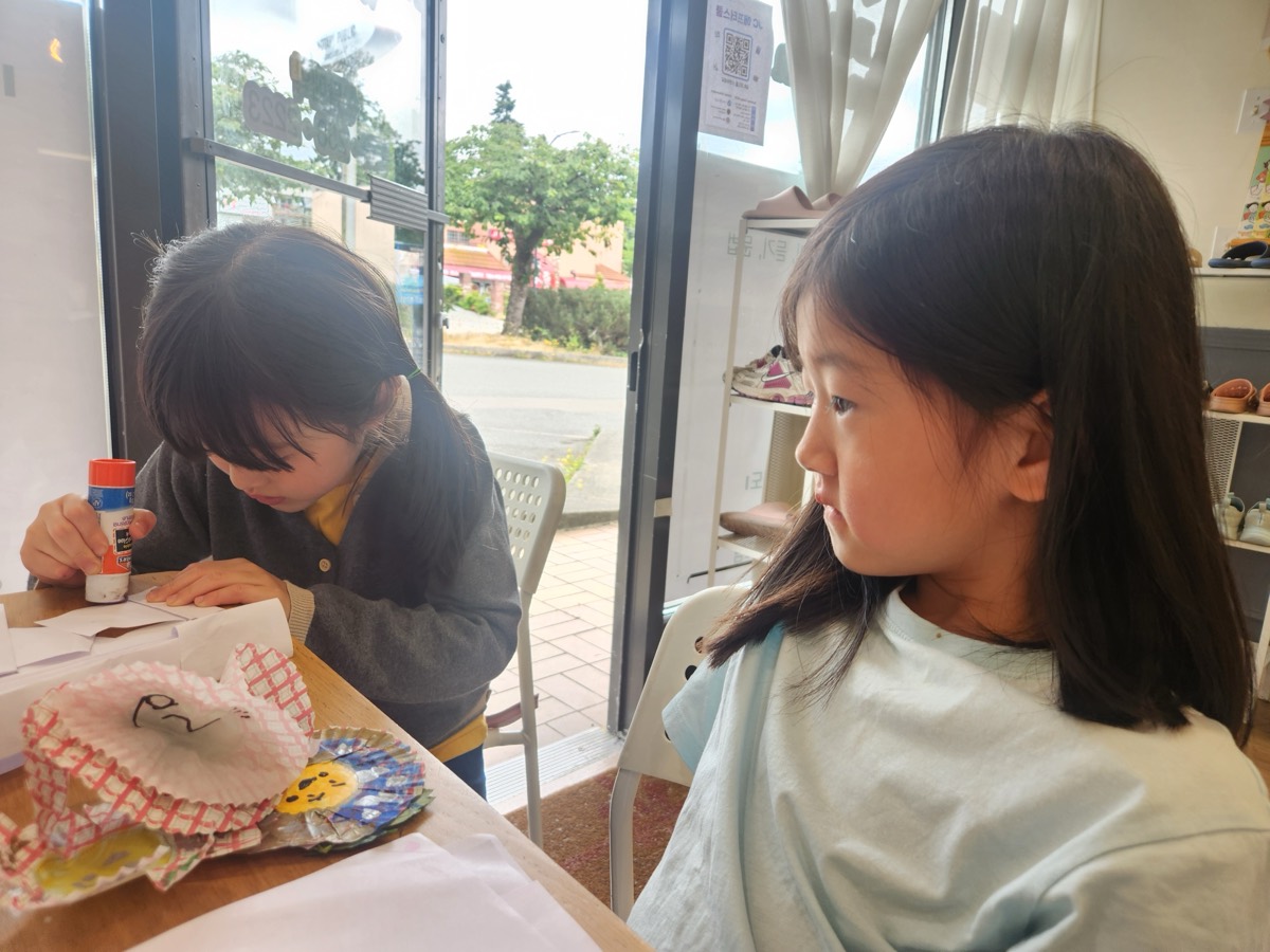 Two children focused on crafts by the window