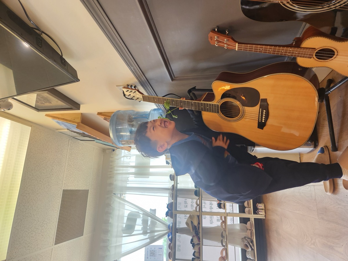 A boy smiling brightly next to a guitar