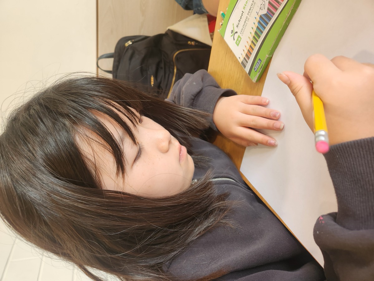 A girl drawing while holding a pencil