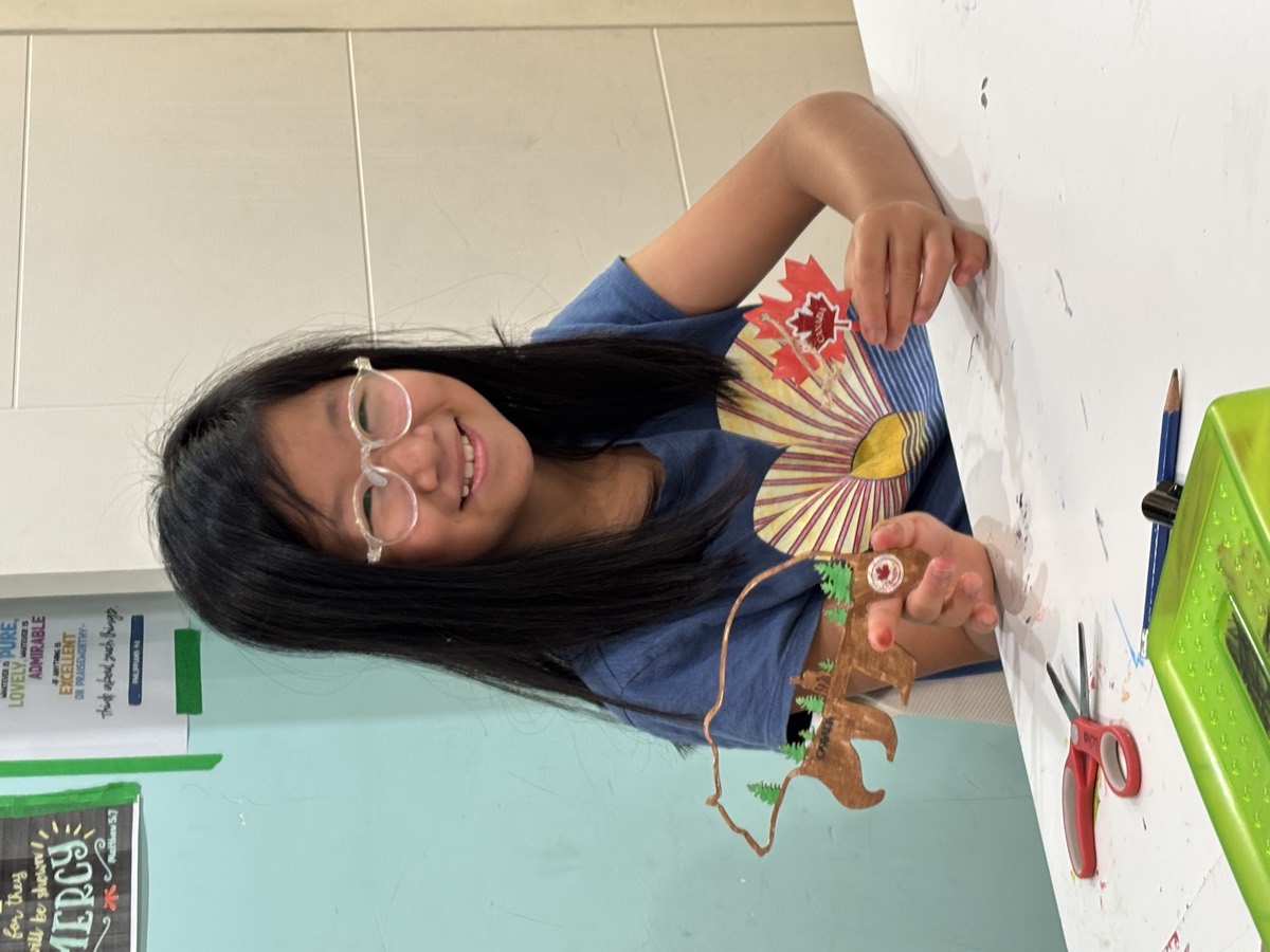 A girl showing her painted bear-and-forest craft