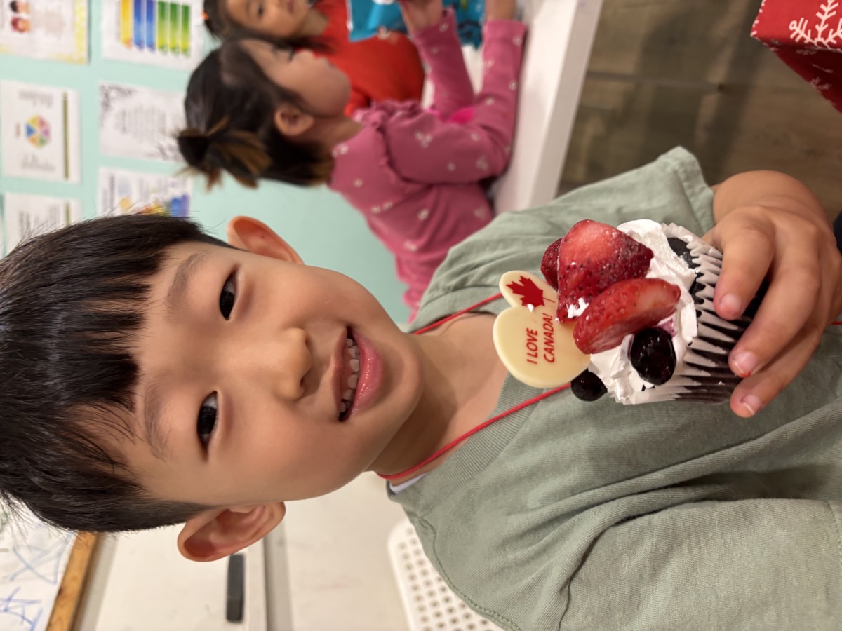 A boy smiling with his I love Canada cupcake