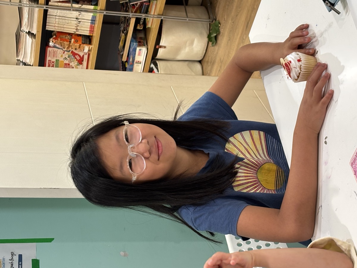 A girl smiling next to her decorated cupcake