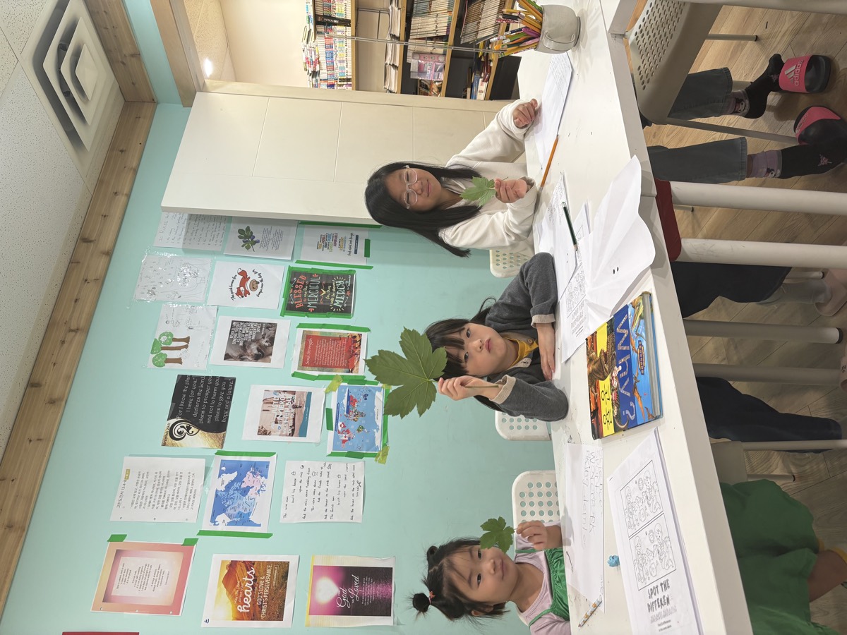 Two children holding up leaves during an English parts-of-speech activity