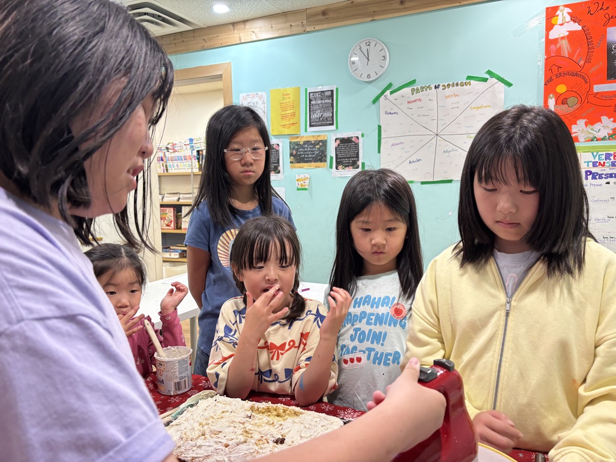 Children gathering around to taste the batter