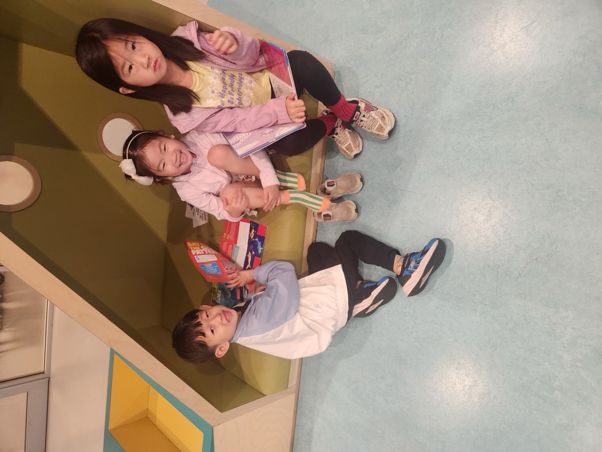 Three children reading in a library nook