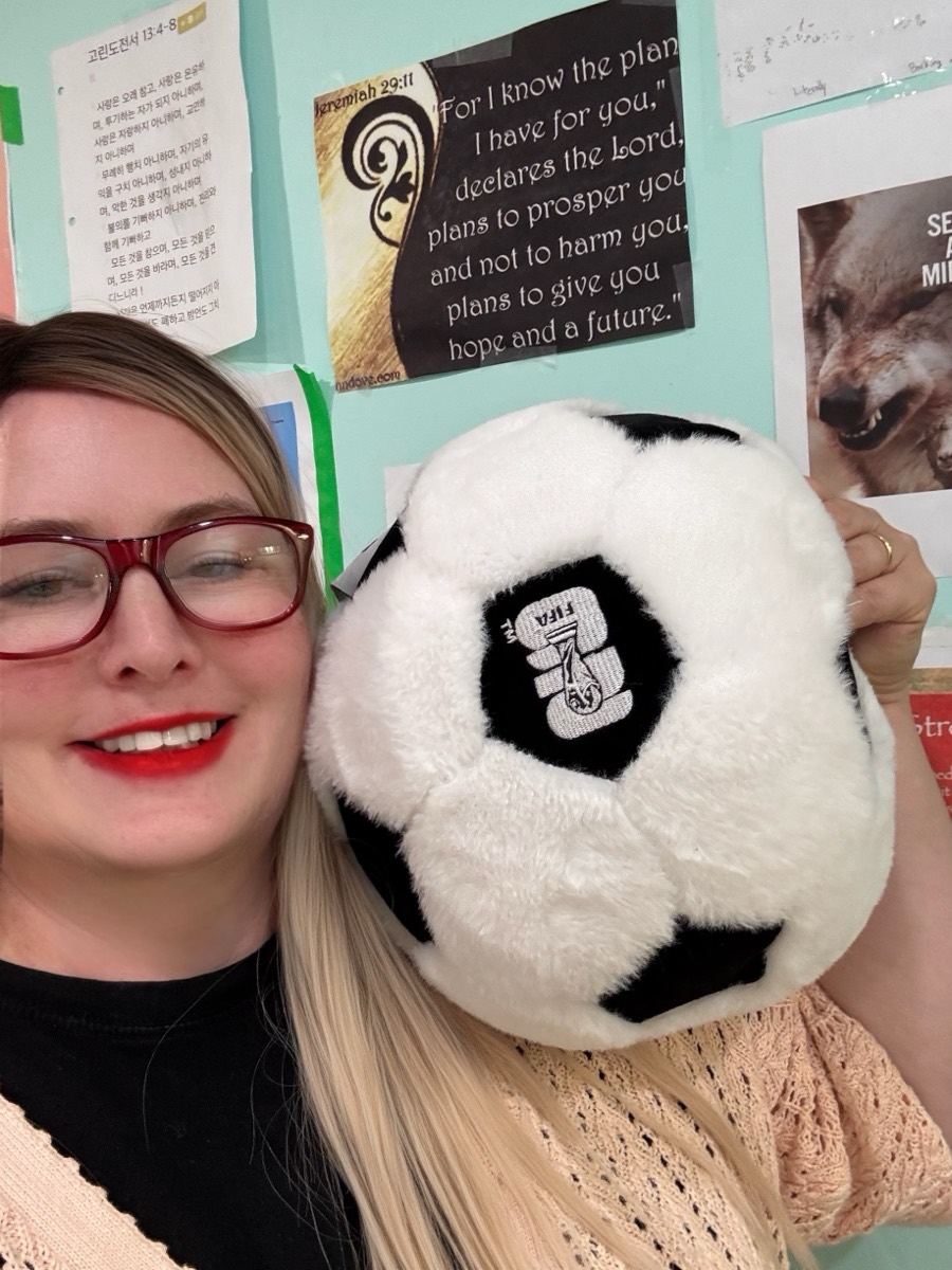 Teacher Diane smiling with the soccer ball plushie
