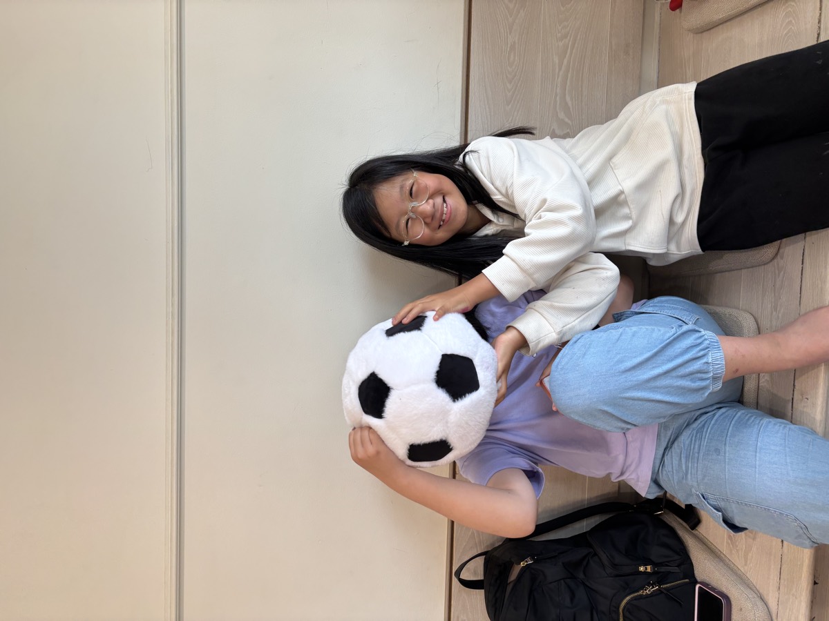 A girl smiling with a soccer ball plushie