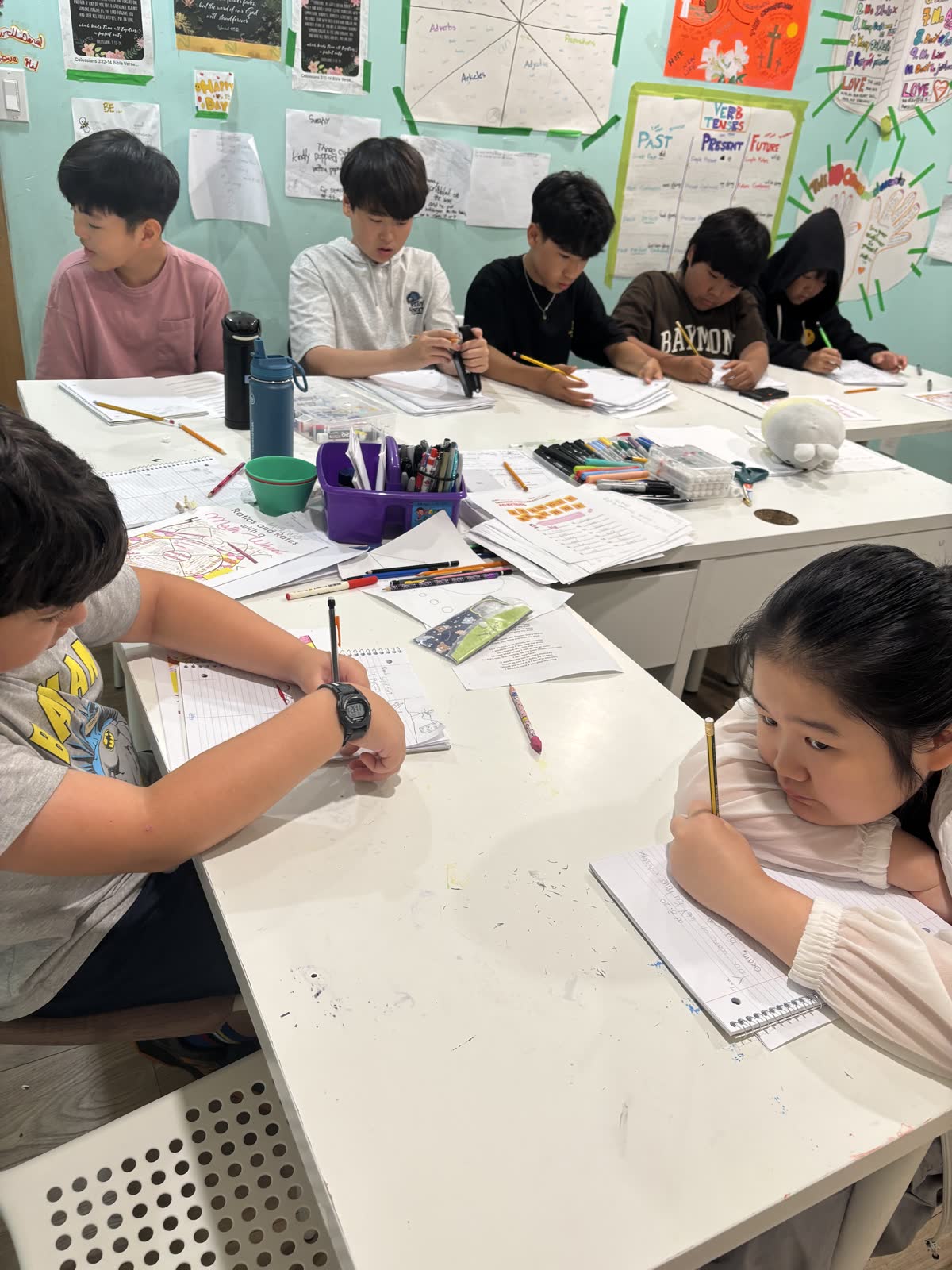 Students writing at a shared classroom table