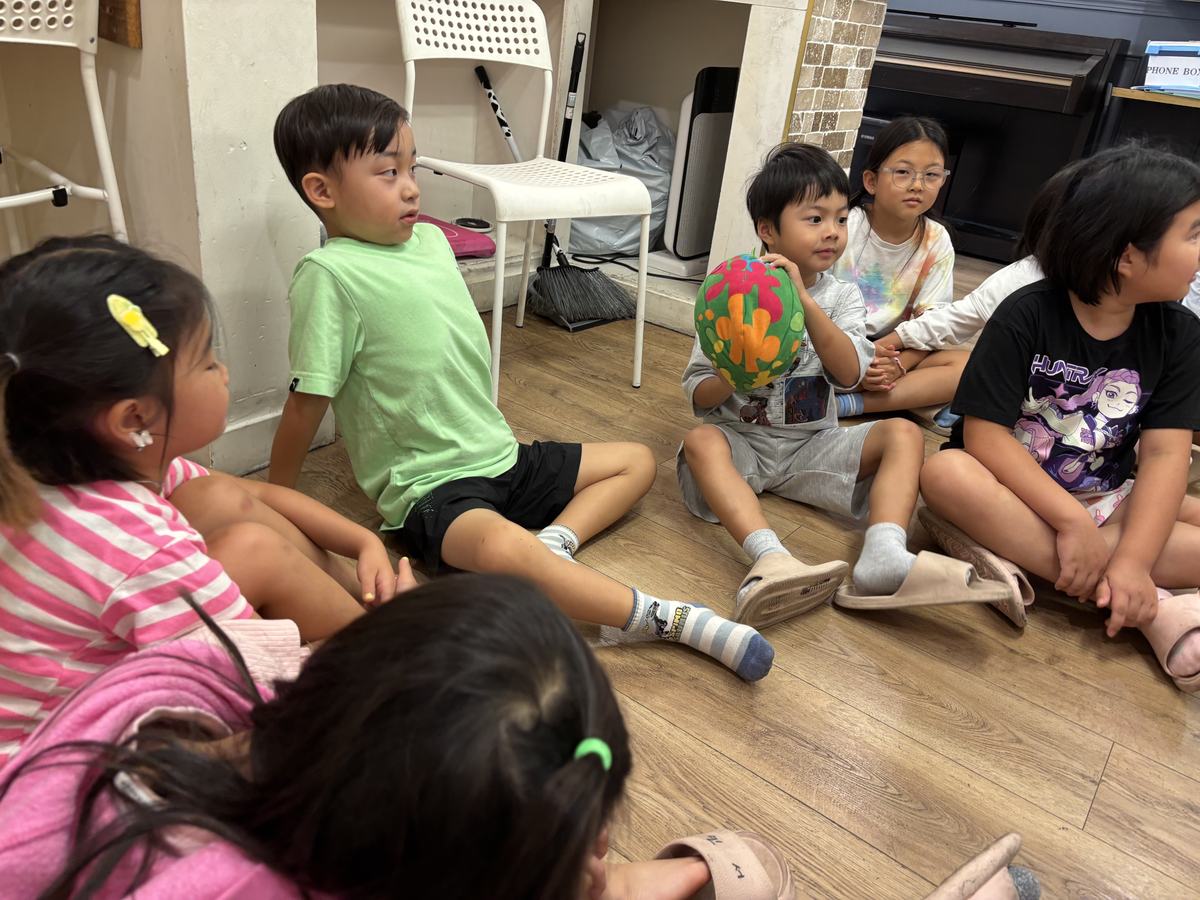 Students sitting cross-legged in a circle on the floor sharing their ideas