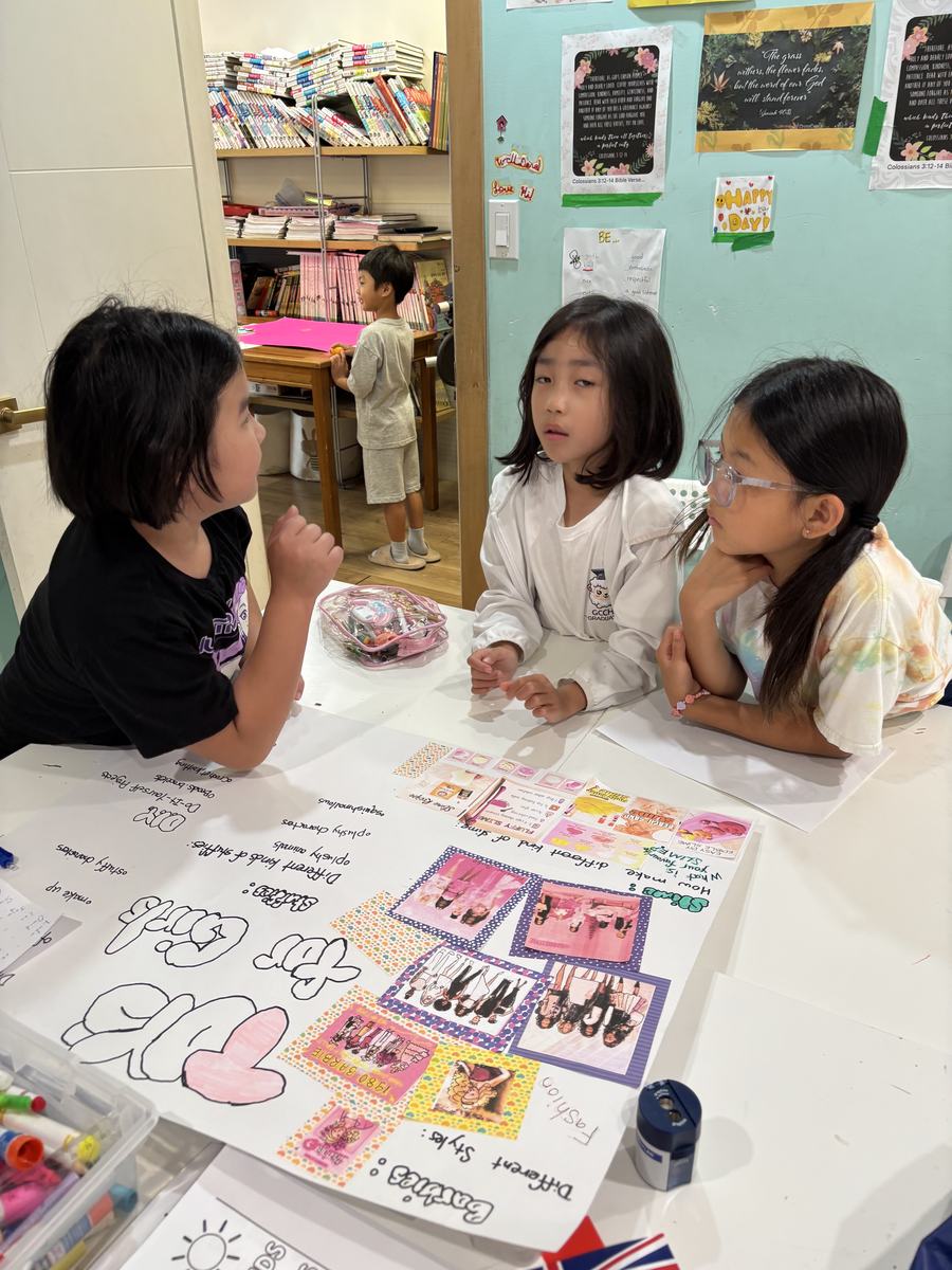 Three students leaning over a poster on the table, talking it through
