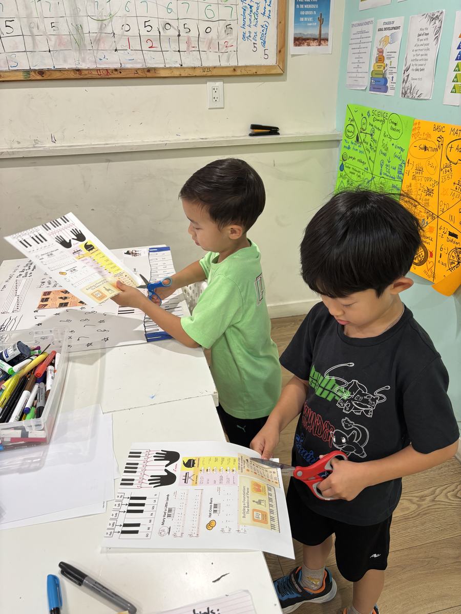 Two students cutting and arranging pieces for their piano poster