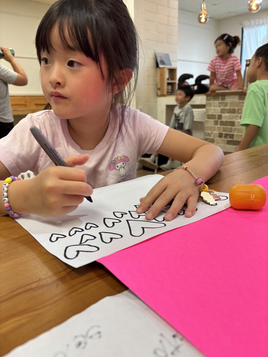 A student carefully drawing large bubble letters for her poster title
