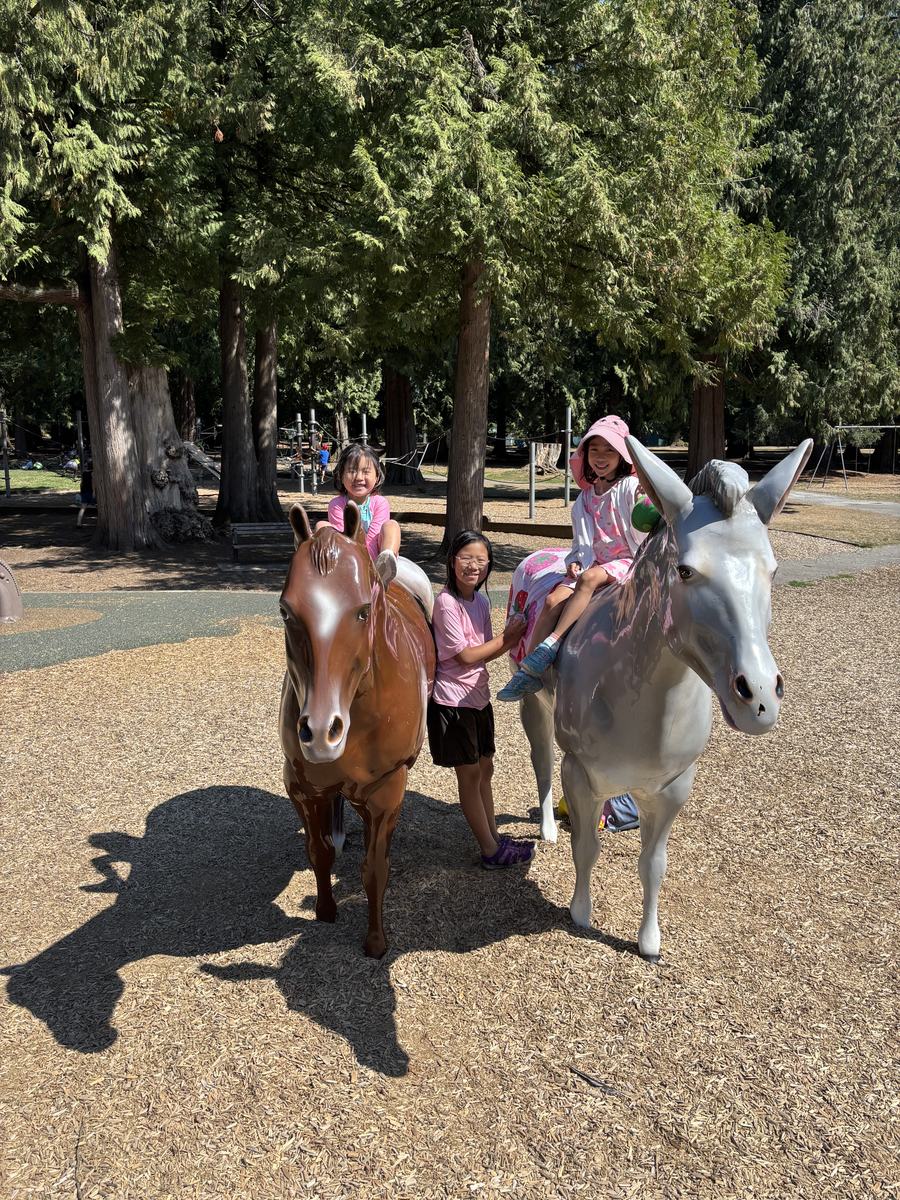 Students posing with the painted horse statues at the park