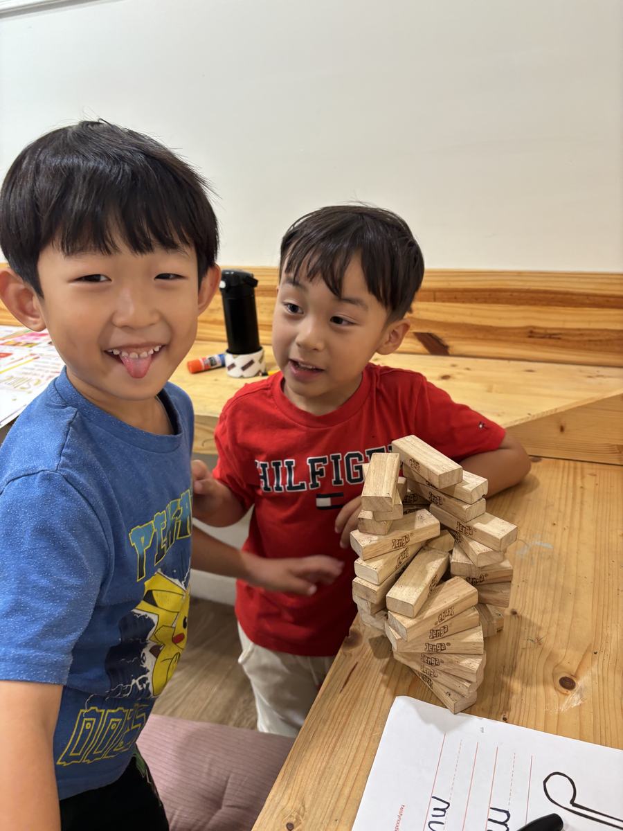 Two students carefully building a tall Jenga tower at the table
