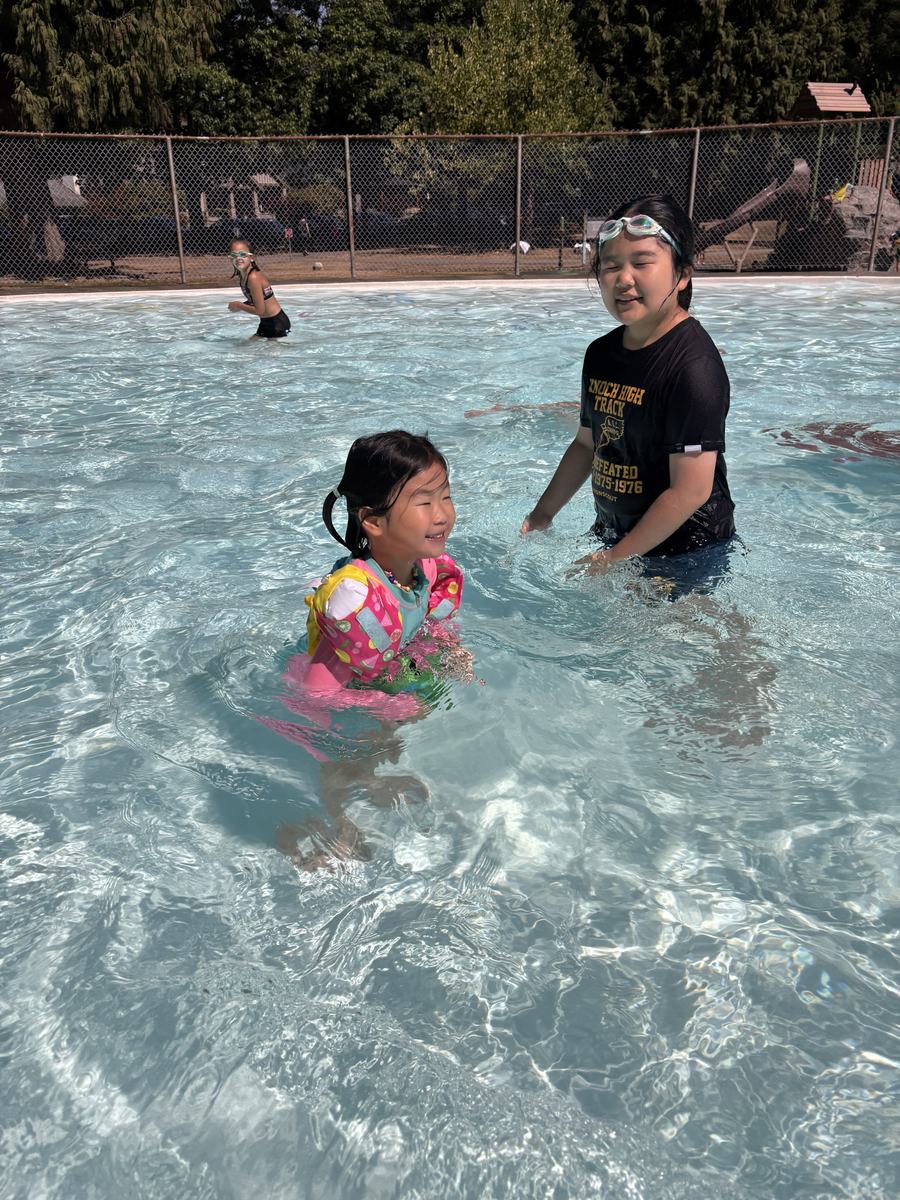 Children playing together in the sunlit outdoor pool