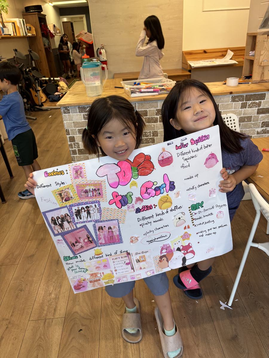 Two students holding up their Toys for Girls poster