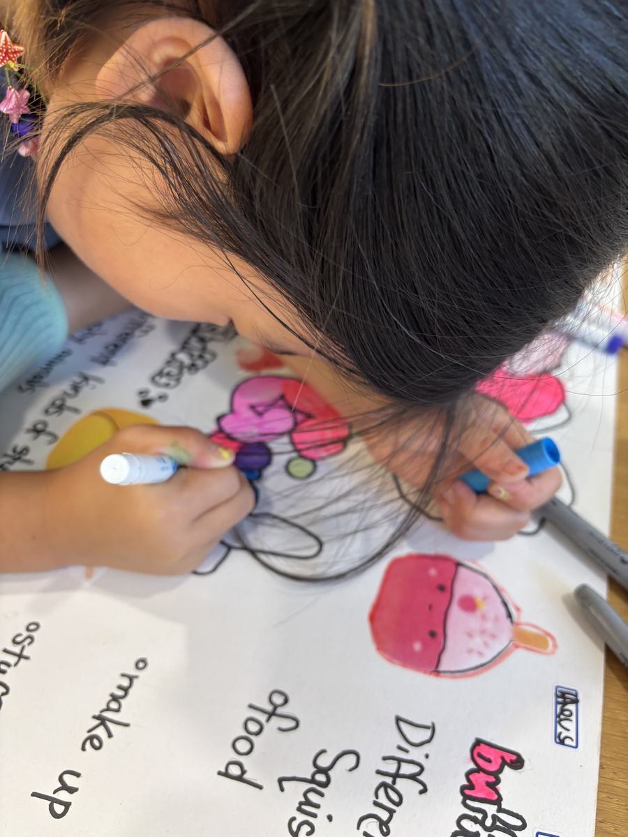 A student colouring in slime illustrations on her poster