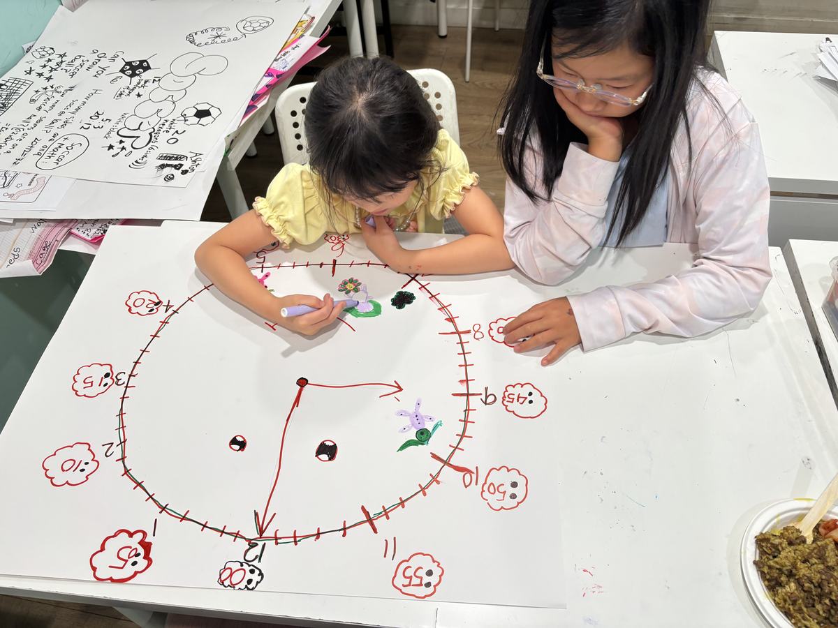 Two students working together on the large clock face, marking the minute ticks