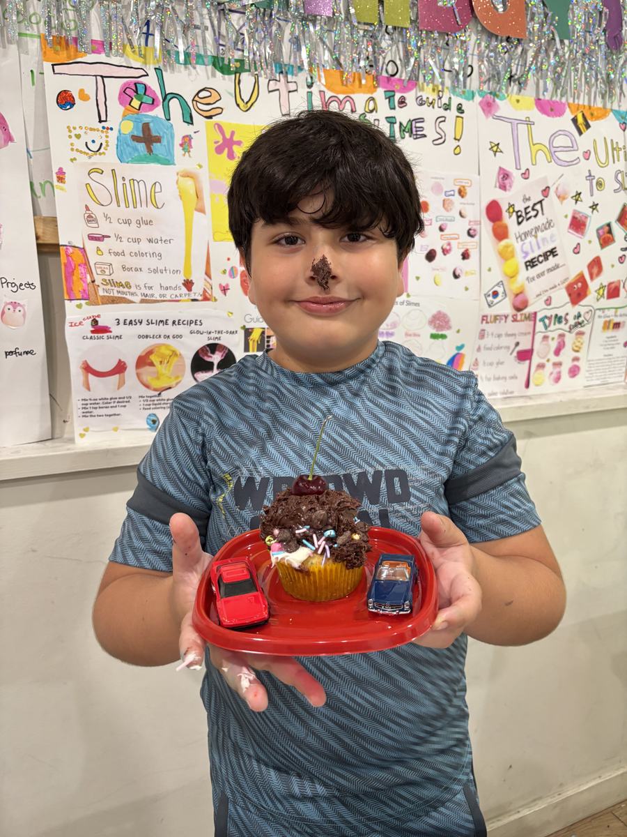 A student presenting his decorated cupcake on a red plate