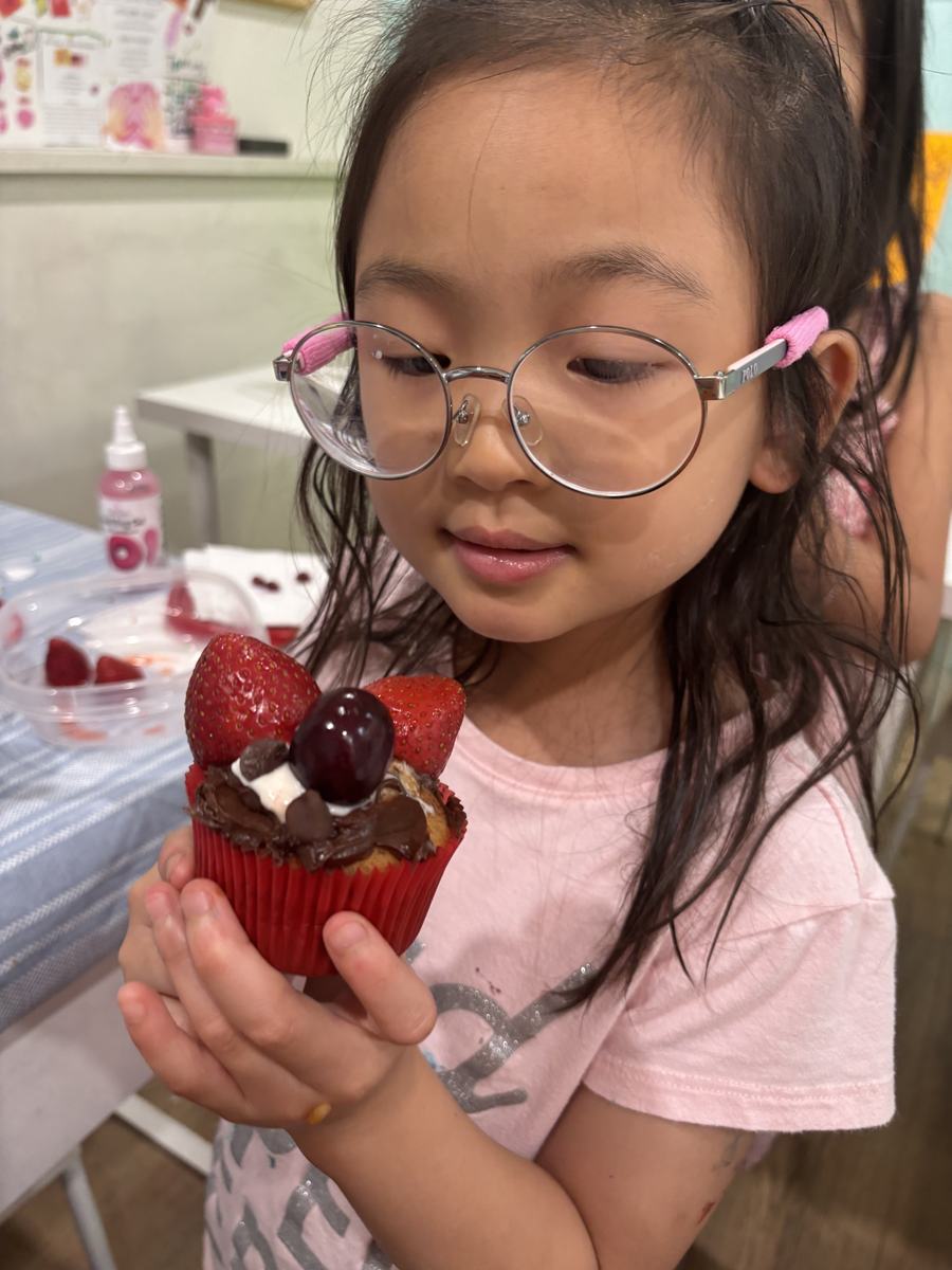 A student holding up her cupcake piled with cream and cherries
