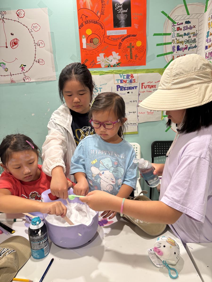 Students gathered around a bowl mixing shaving cream and glue
