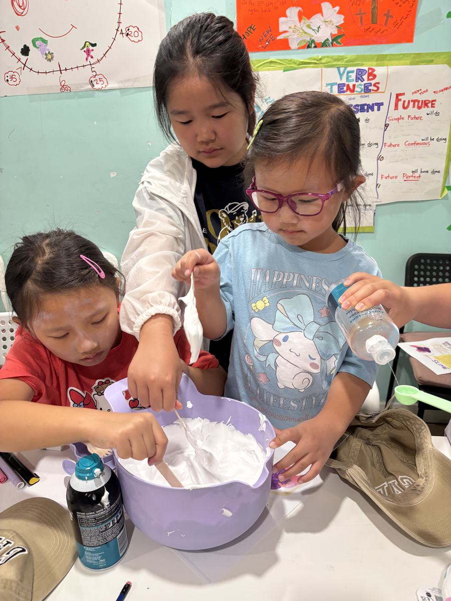 Two students stirring the slime mixture in a purple bowl