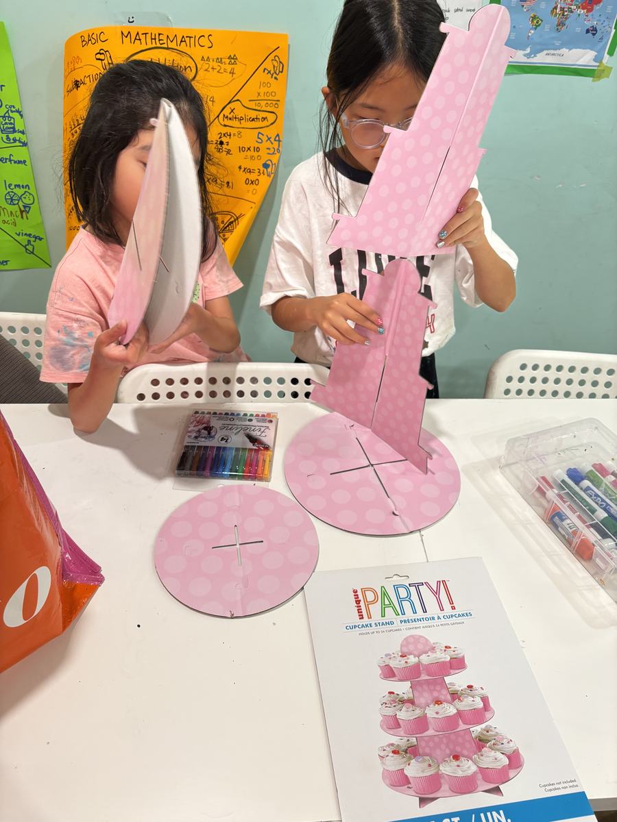 A student pulling a long strand of pink slime high into the air