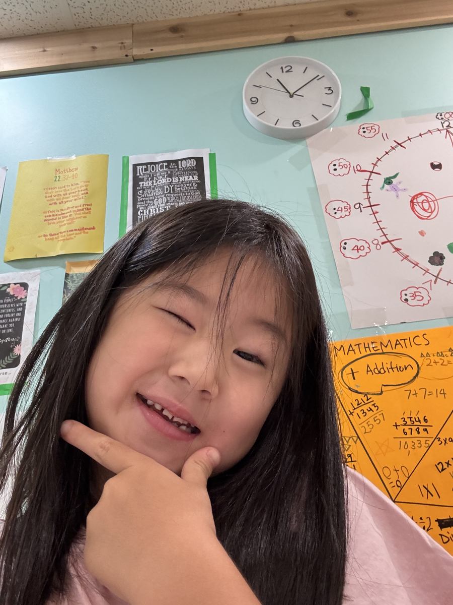 A student grinning at the camera in the classroom