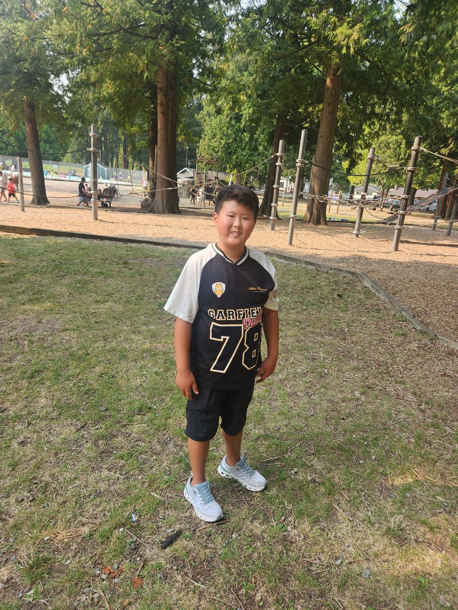 A student standing on the grass smiling at the camera