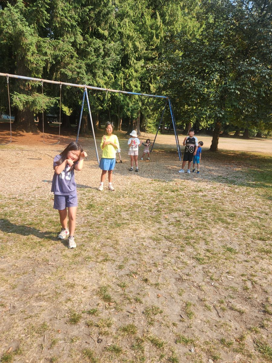 A student on the swings with friends behind her at the park