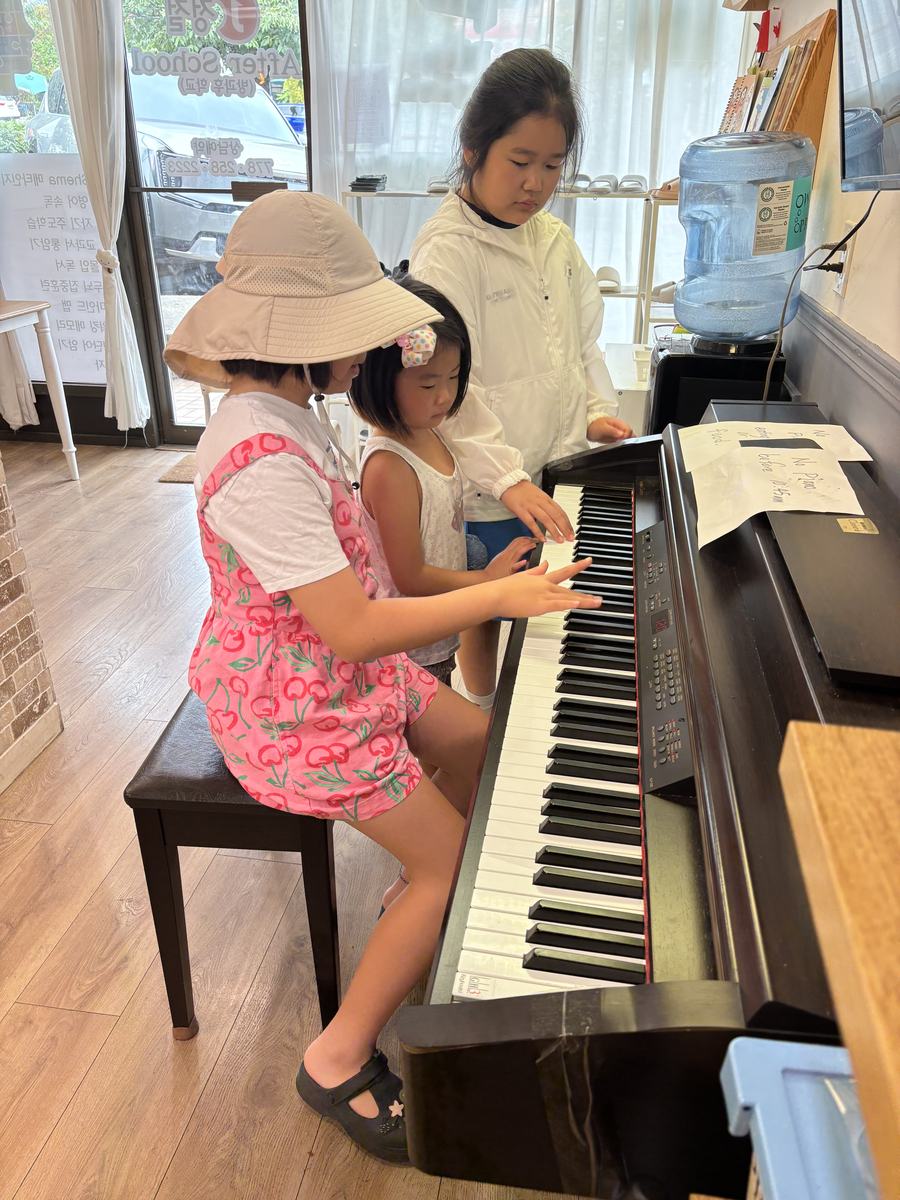 Students taking turns at the piano keyboard, one pointing to the next key