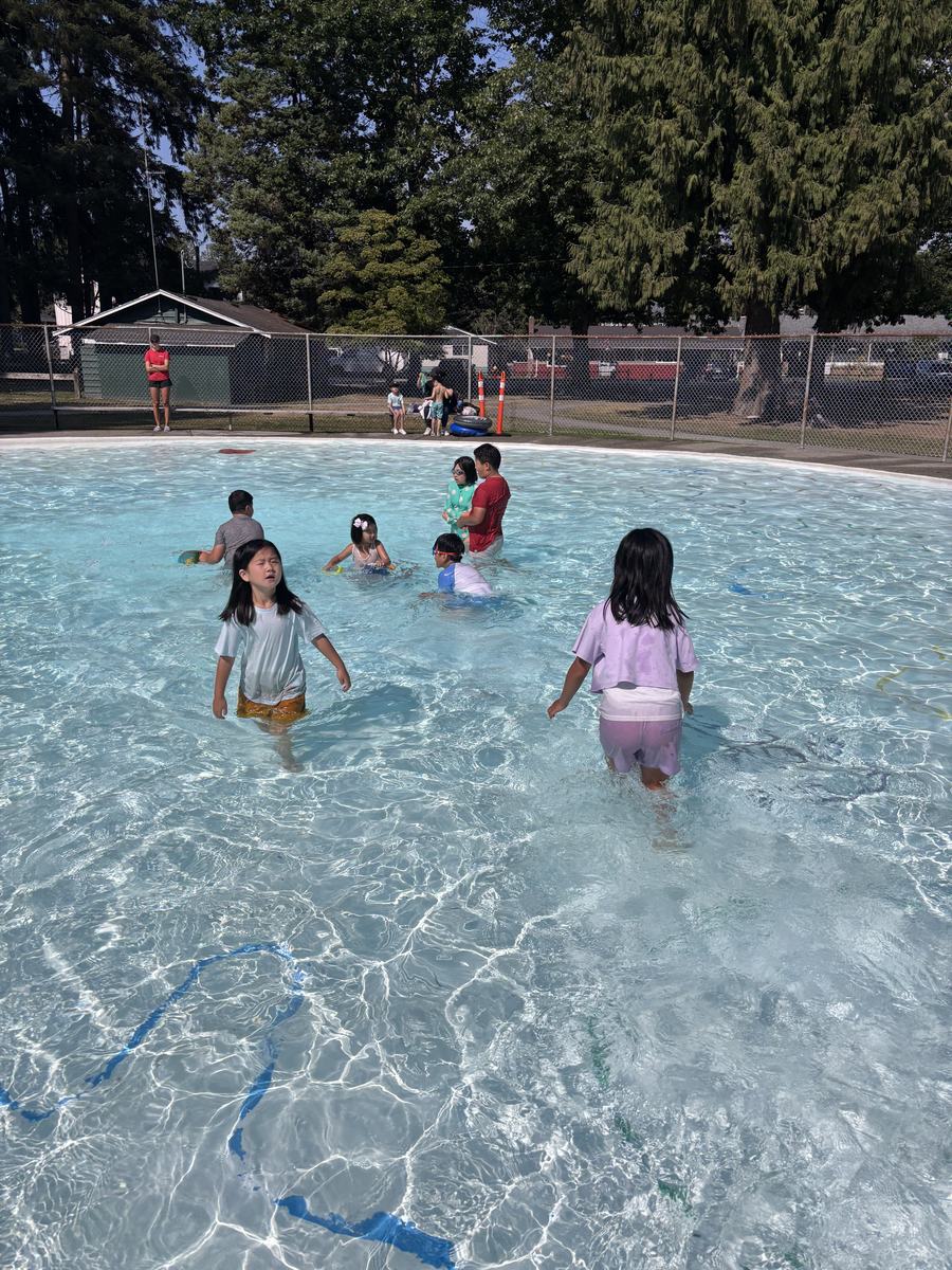 Students wading and splashing across the wide outdoor pool