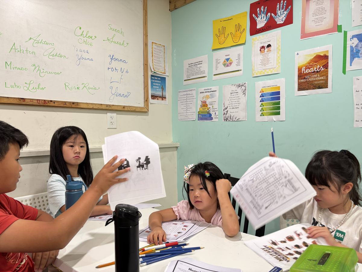 Students around the classroom table holding up their finished worksheets