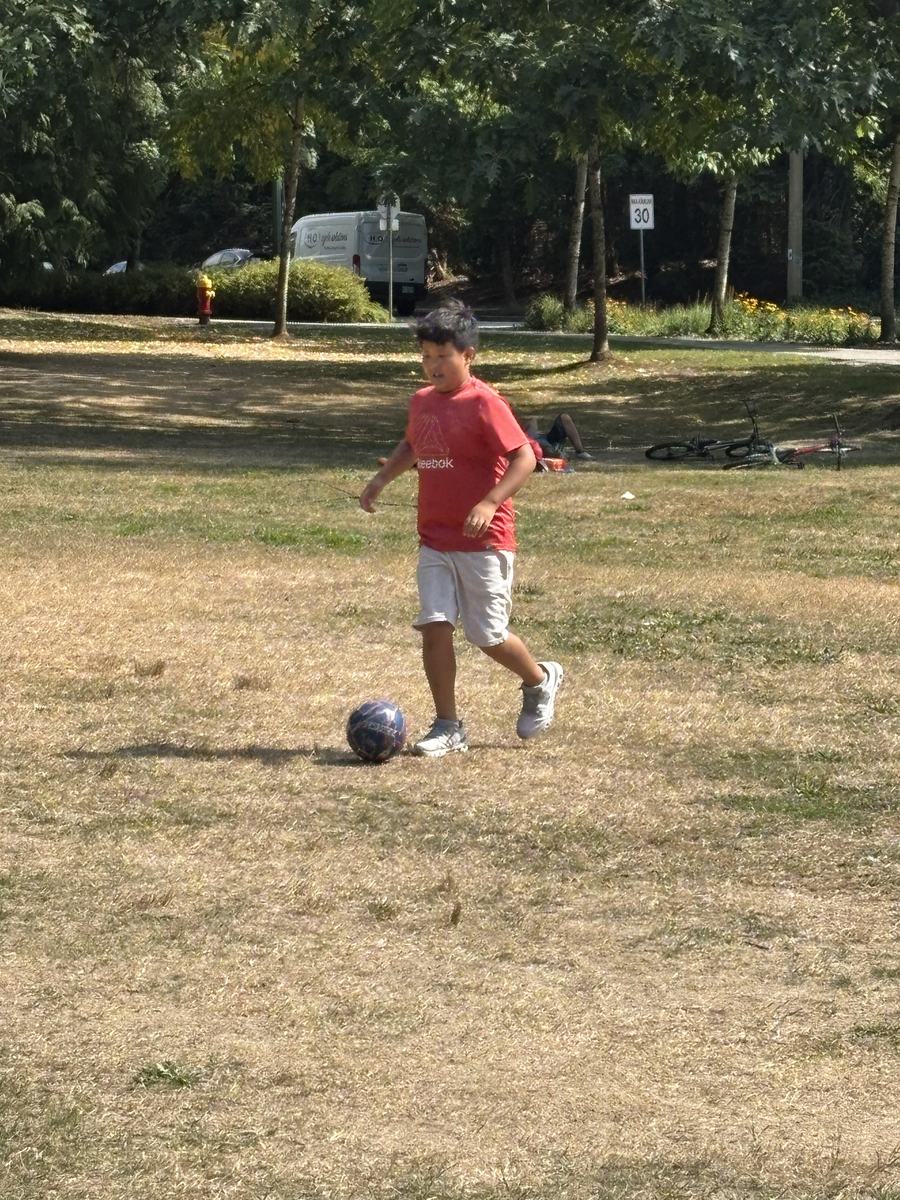 A student running to the ball on the dry grass field
