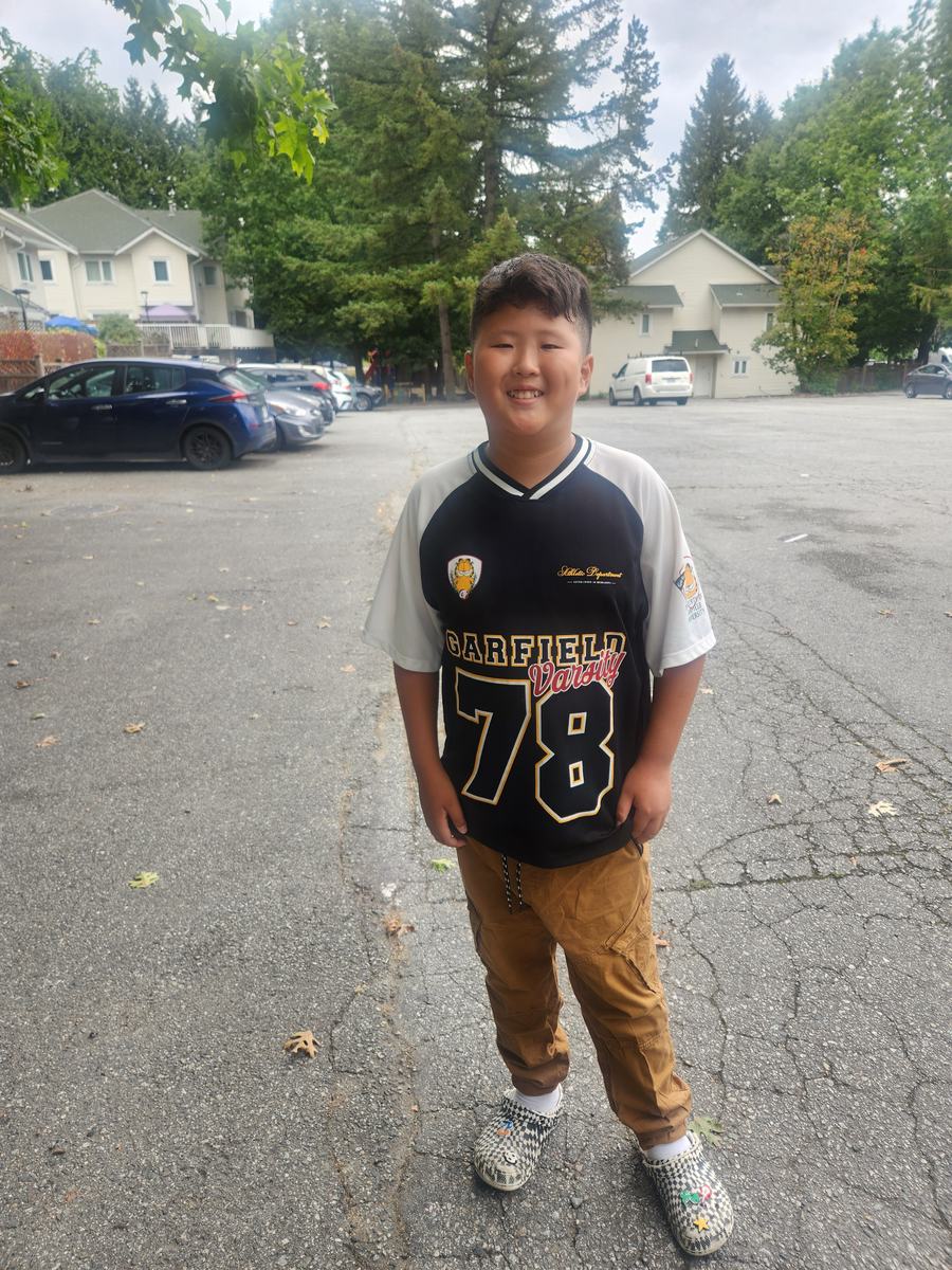 A student standing in the driveway in his soccer jersey, ready to head home