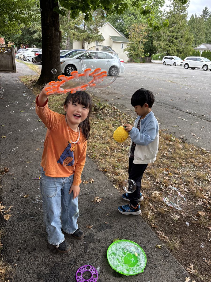 A student holding up a large orange bubble wand and laughing