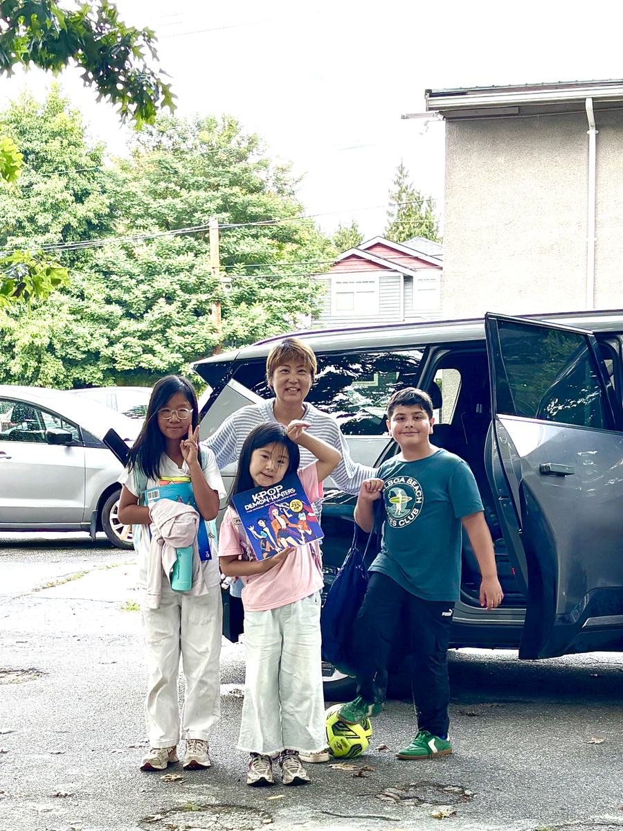 Four students standing beside the open car door holding their certificates