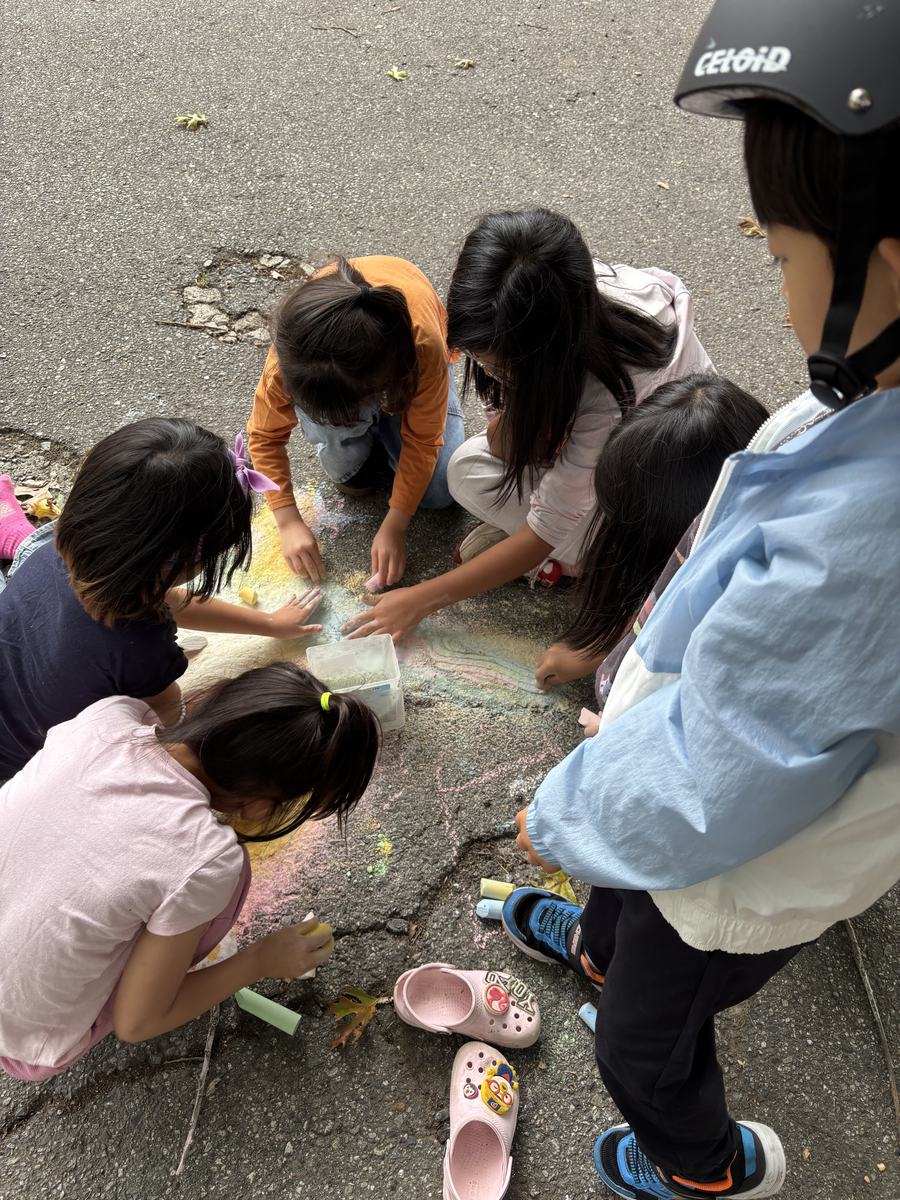 Students crouched on the pavement drawing with coloured chalk