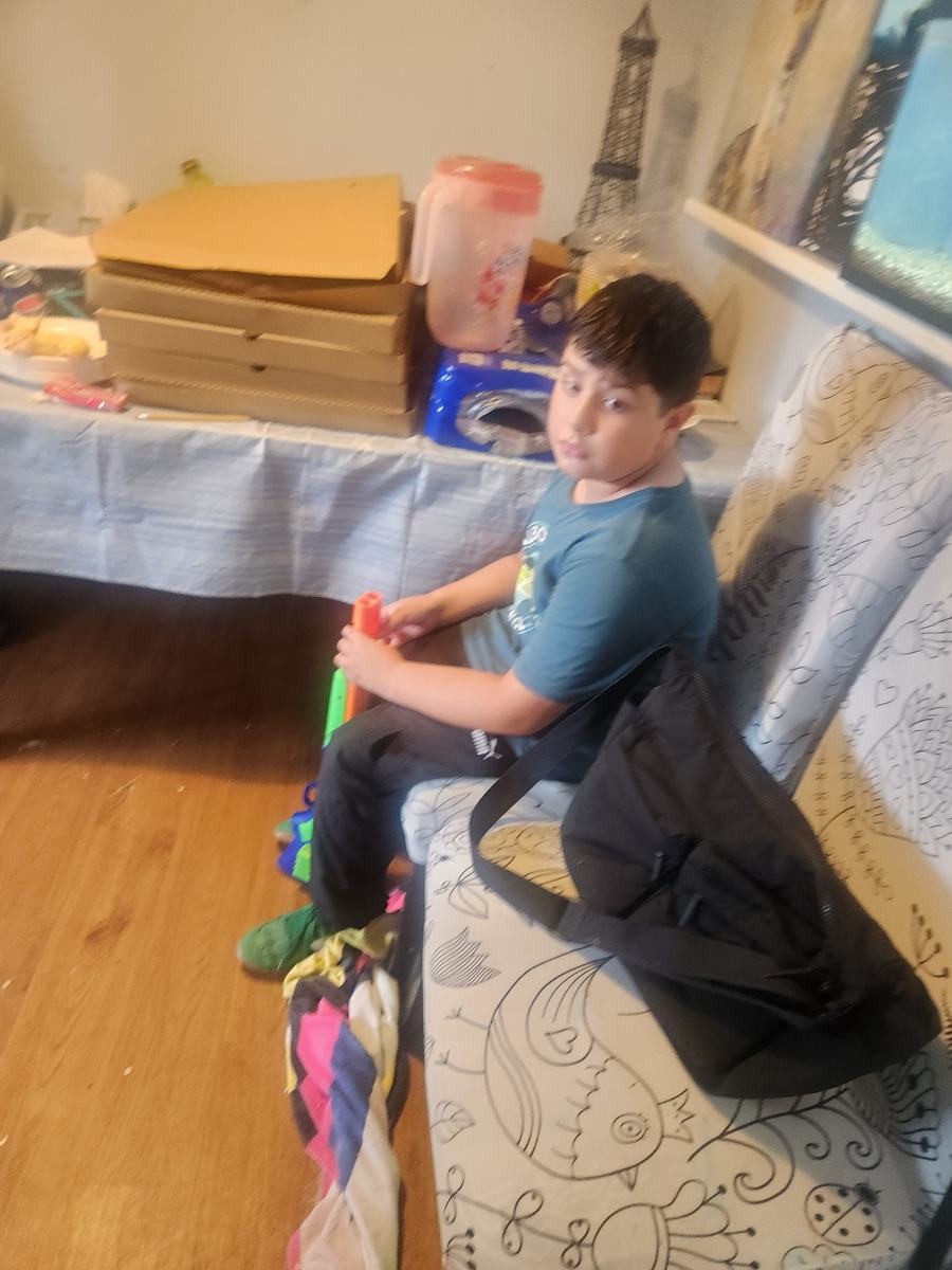 Stacked pizza boxes and a juice pitcher on the table, with a student sitting nearby holding his backpack