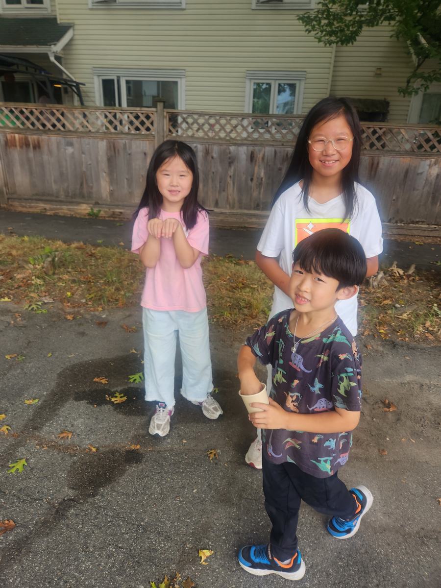 Three students posing together in the driveway outside the house
