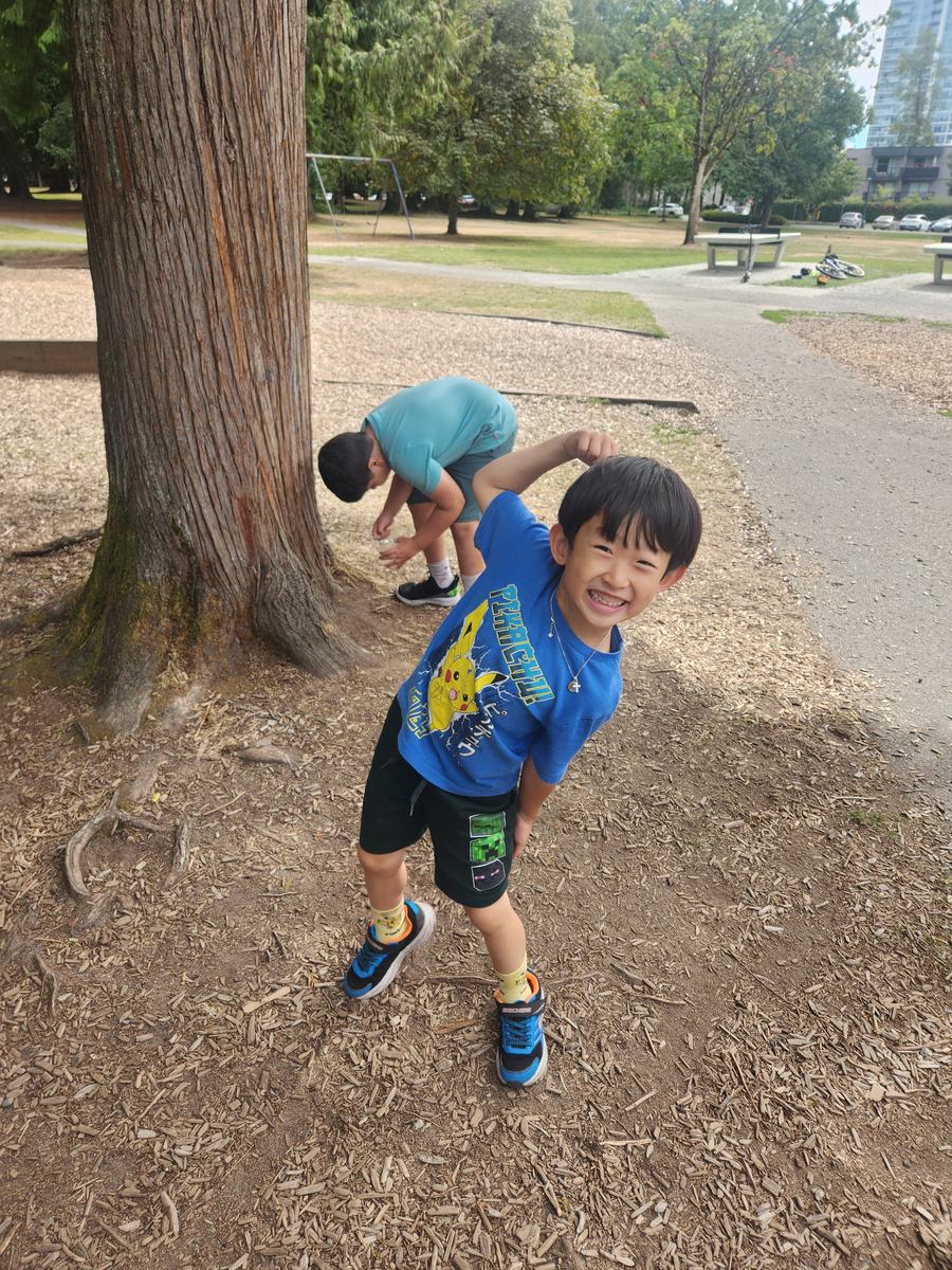 A student striking a pose for the camera under a huge cedar trunk