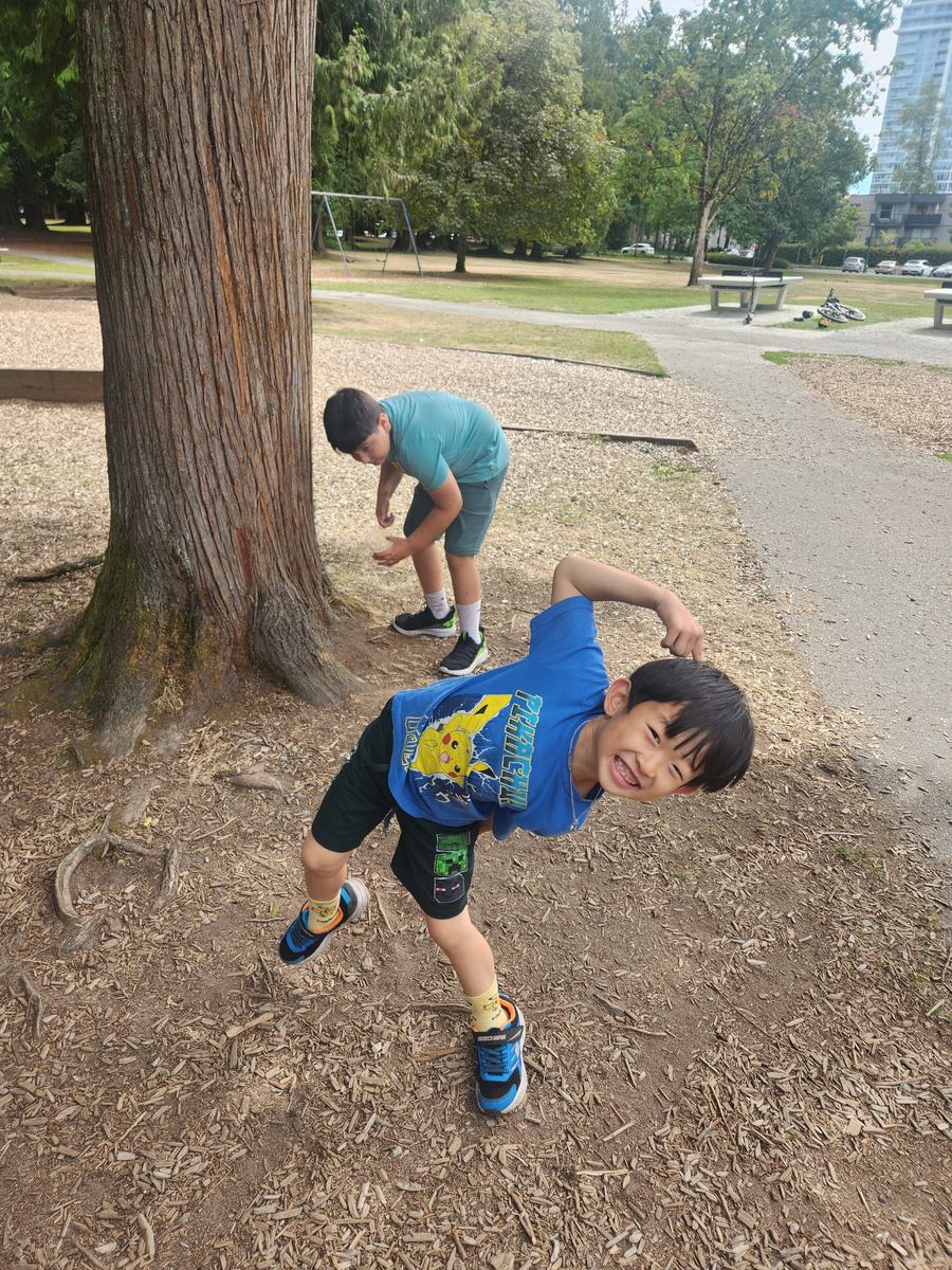 Two students goofing around beside the big tree on the wood-chip path