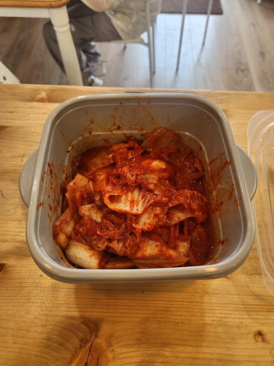 A container of kimchi on the wooden lunch table