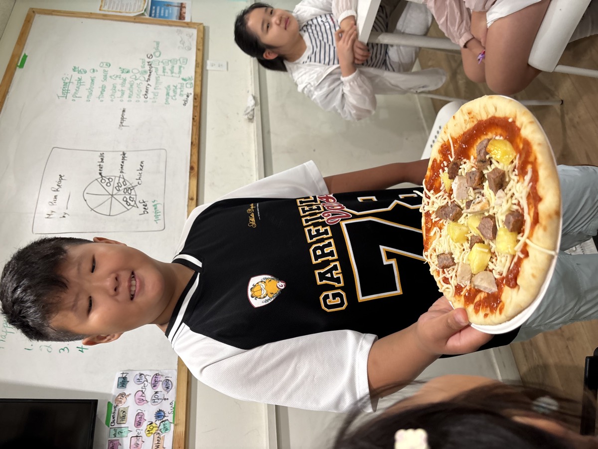 A student holding up his baked pizza topped with mushrooms and meat