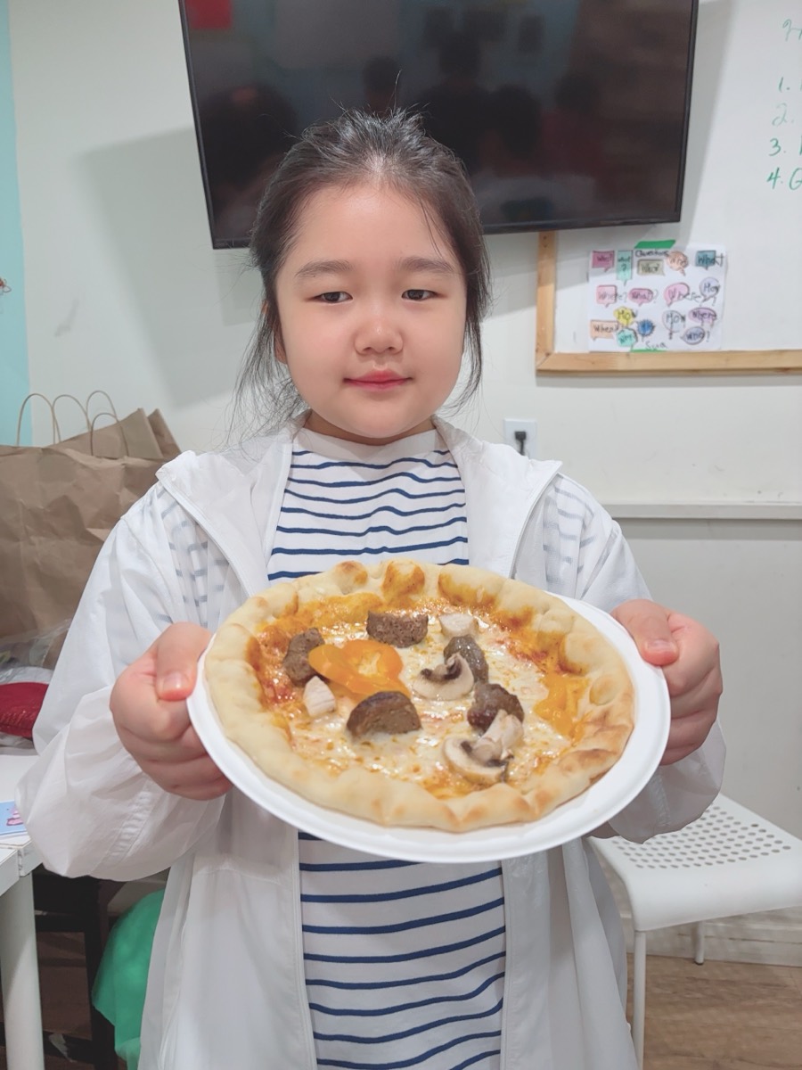 A student holding her baked mushroom and cheese pizza on a plate