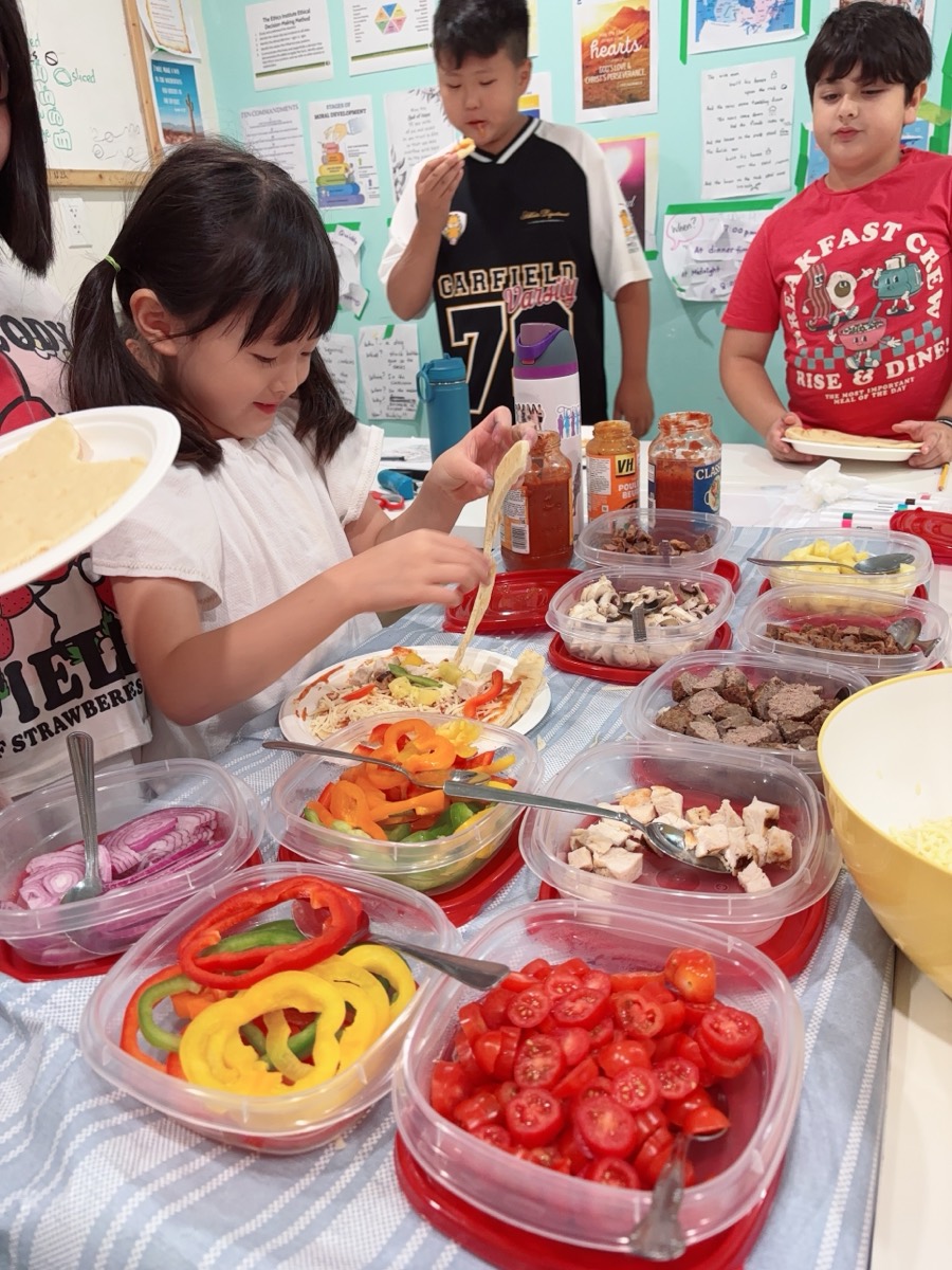 A student adding sliced bell peppers to her pizza