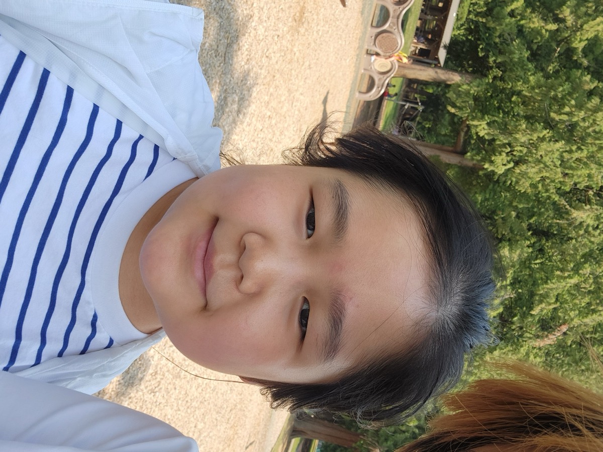 A young camper smiling at the camera outdoors on a sunny day