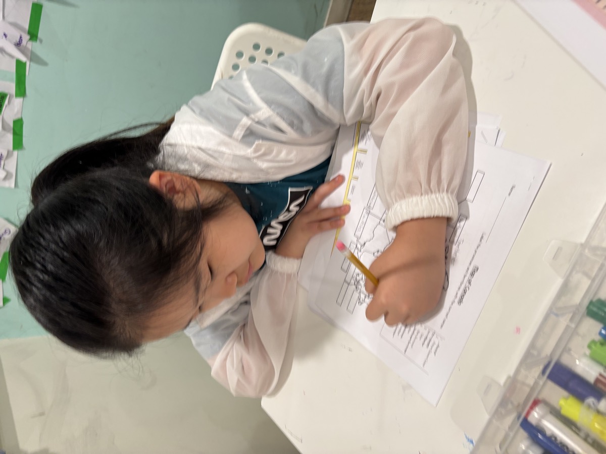 A younger student writing labels onto her map of Canada