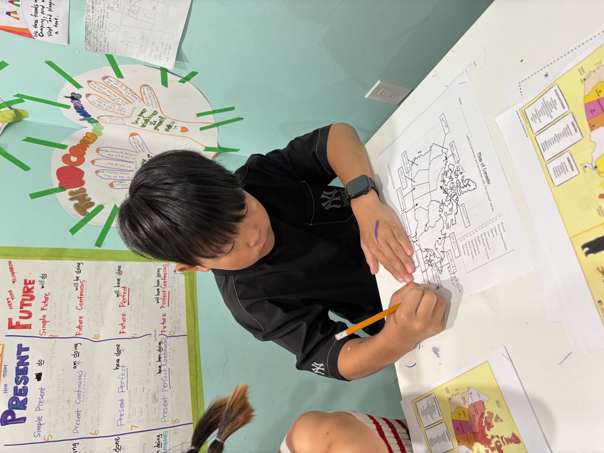 A student concentrating as he writes province names onto his outline map