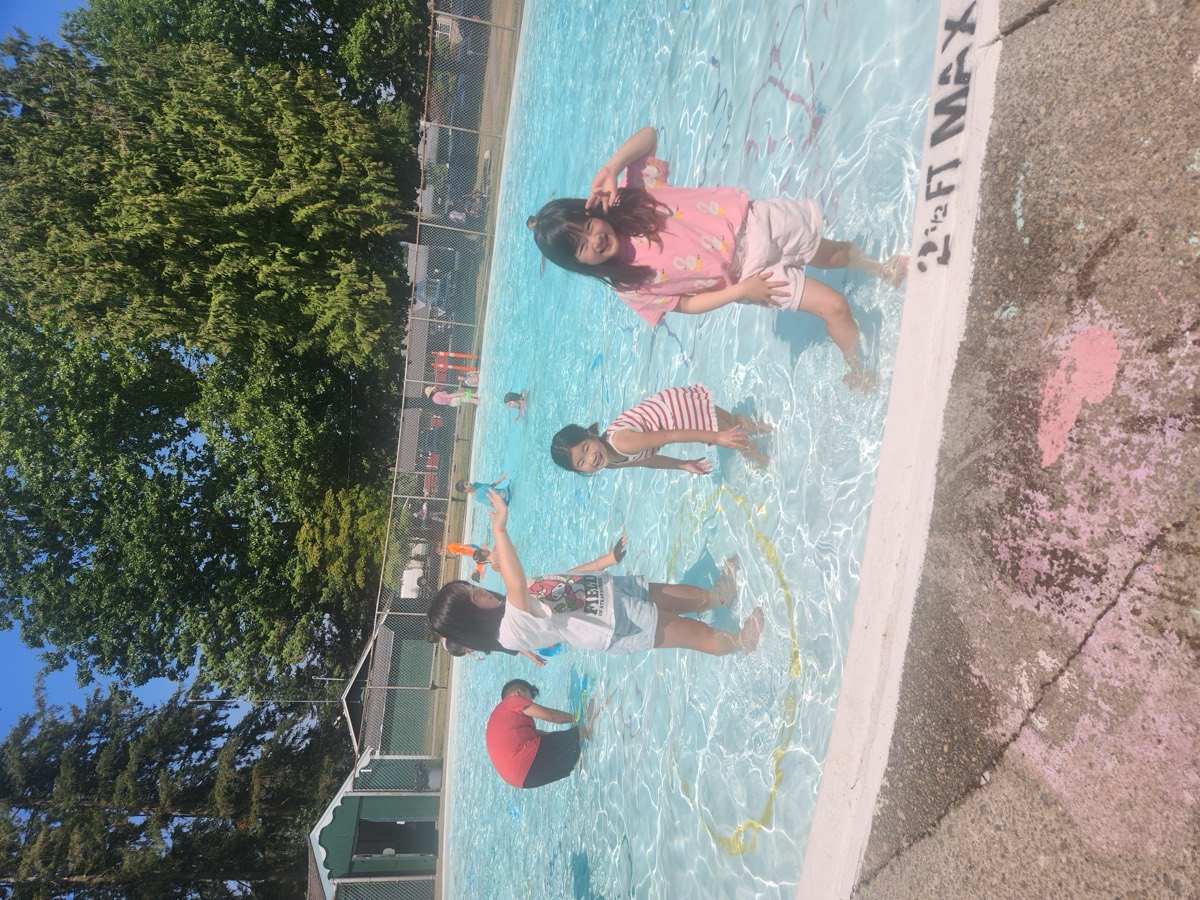 Children playing together in a sunny outdoor pool
